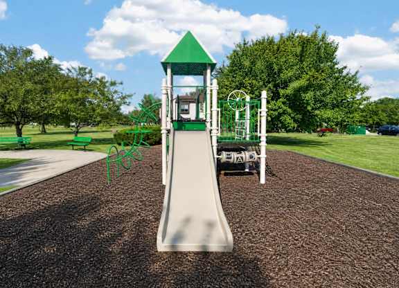 A playground with a green slide and a white tower.