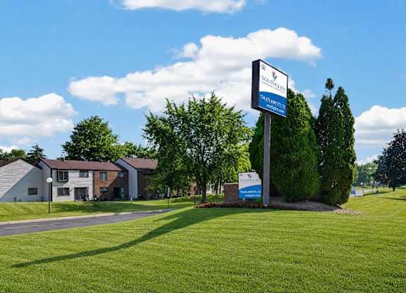 A sign for Sunrise Senior Living stands in a grassy field.