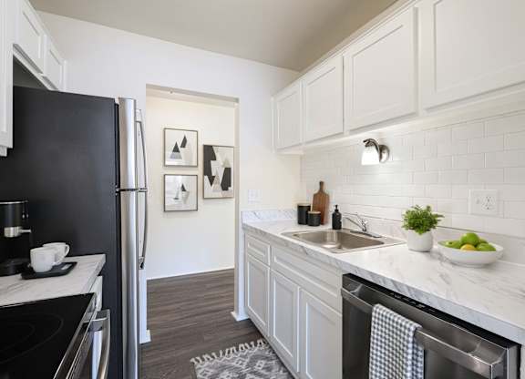 A kitchen with a black fridge and white cabinets.