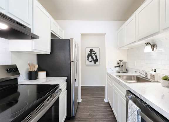 A kitchen with black appliances and white cabinets.