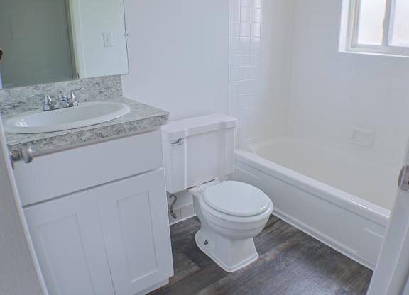 A white toilet sits in a bathroom next to a sink and bathtub.