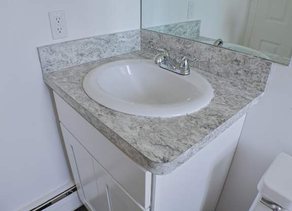 A white sink is on a marble countertop.