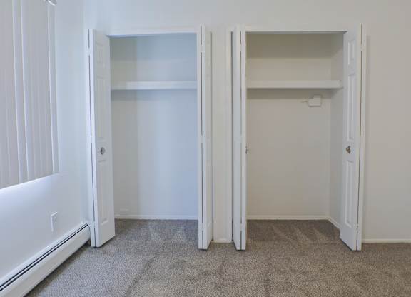 A white room with two open doors and a carpeted floor.