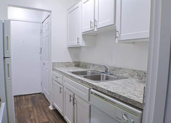 A kitchen with white cabinets and a marble countertop.