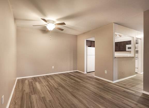 A room with a ceiling fan and wooden flooring.
