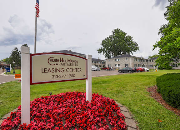 A leasing center sign for Cherry Hill Manor apartments is in front of a building.