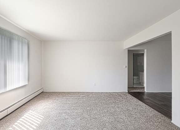 A large, empty room with a carpeted floor and a doorway leading to another room.