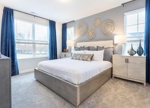 A bedroom with a large bed and a window with blue curtains.