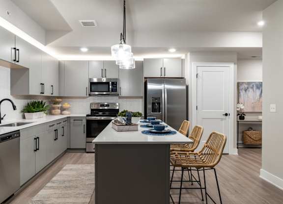 an open kitchen with stainless steel appliances and a large island with chairs