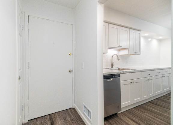 A kitchen with white cabinets and a wooden floor.