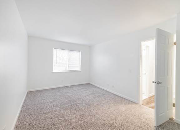 A room with a carpeted floor and a window.