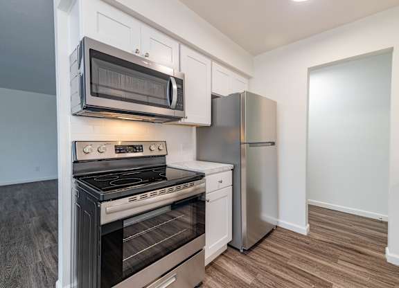 A kitchen with a stove, oven, refrigerator, and microwave.