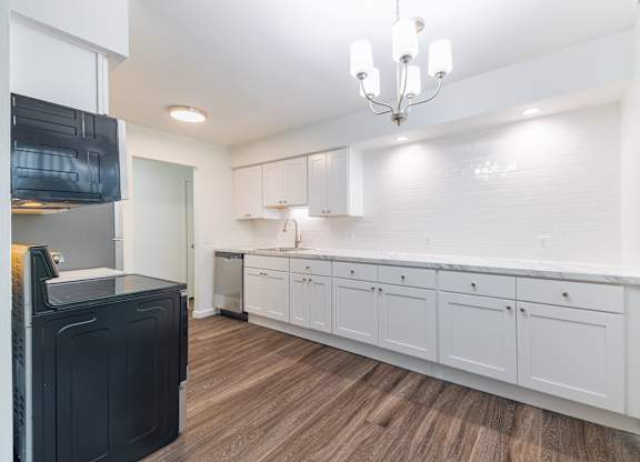 A kitchen with white cabinets and a black fridge.