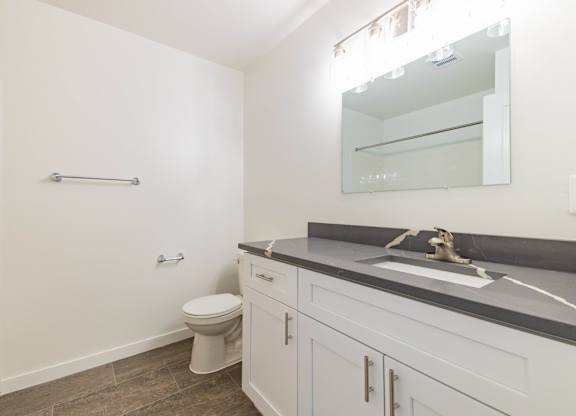 A white bathroom with a toilet, sink, and mirror.