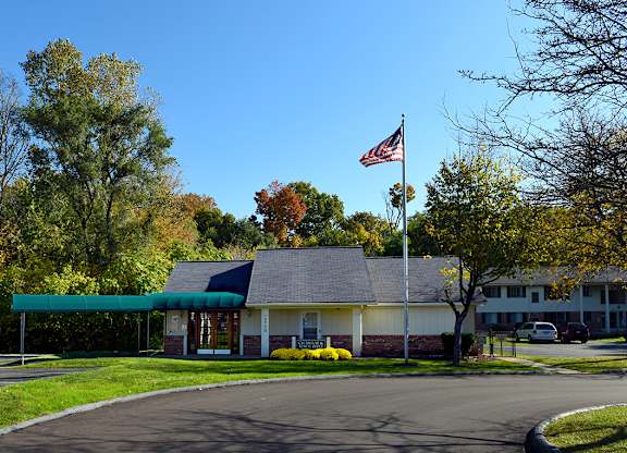A building with a flag on top is surrounded by trees.