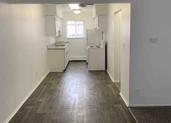 A kitchen with white appliances and a window.