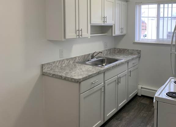 A kitchen with white cabinets and a marble countertop.