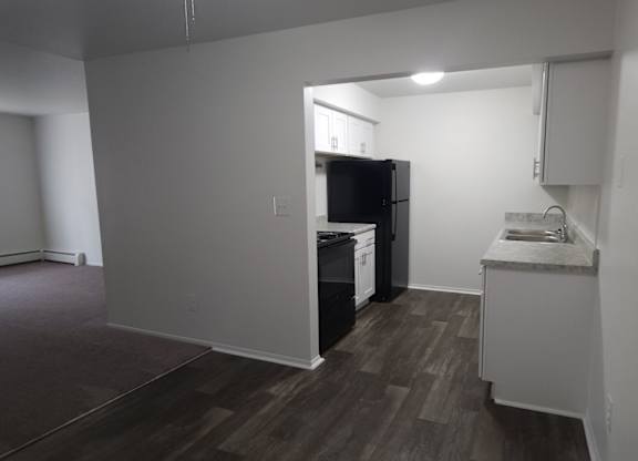 A kitchen area with a refrigerator, sink, and cabinets.