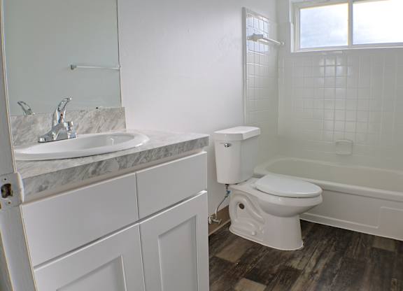 A white bathroom with a marble sink and toilet.