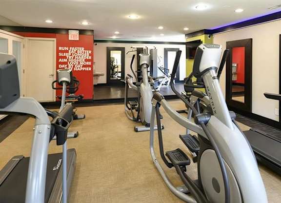 a gym with several pieces of exercise equipment and mirrors