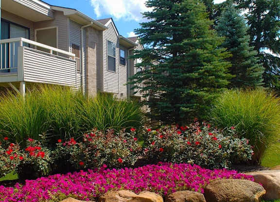 a garden in front of a house with trees and flowers