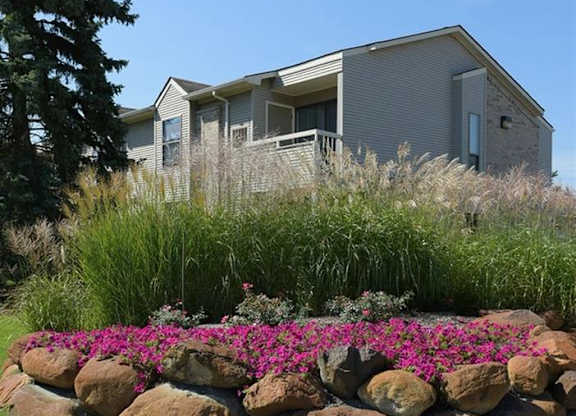 a house with a stone wall and flowers in front of it