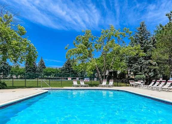a swimming pool with chairs and trees next to it