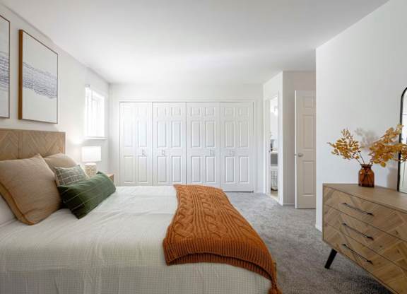 A bedroom with a bed, dresser, and two framed pictures on the wall.