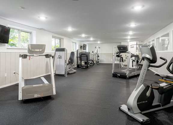 A gym with a variety of exercise equipment including treadmills, stationary bikes, and weight machines.