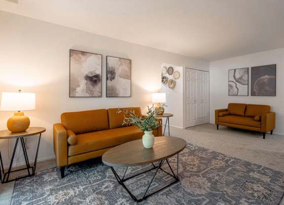 A living room with a brown sofa, a round table, and a rug.