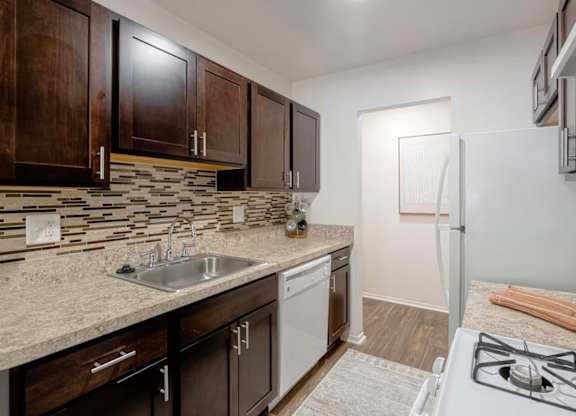A kitchen with a white stove top oven and a white dishwasher.