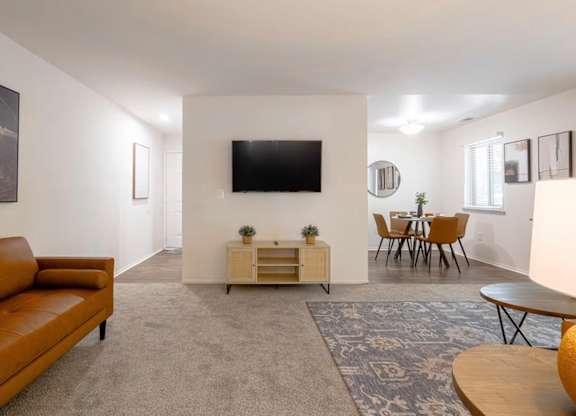 A living room with a brown couch and a flat screen TV mounted on the wall.