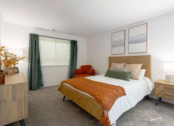 A bedroom with a bed, nightstand, and a window with curtains.