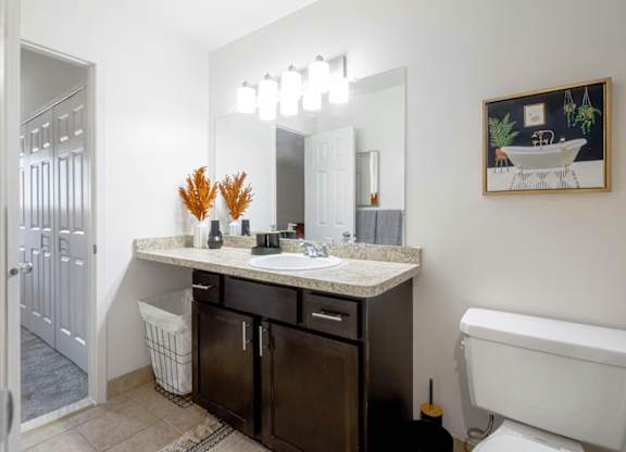 A bathroom with a white tub, sink, and a mirror.