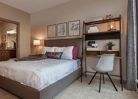 A bedroom with a bed, desk, and chair.
