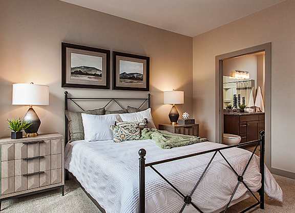 A bedroom with a bed, nightstand, and two lamps.