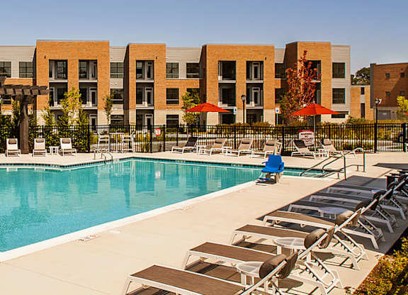 A large swimming pool surrounded by sun loungers and umbrellas.