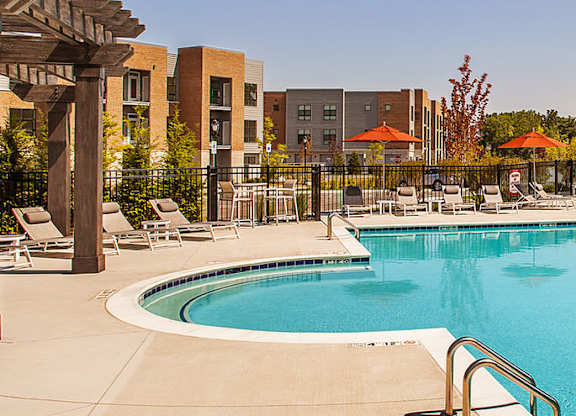 A large swimming pool surrounded by lounge chairs and umbrellas.