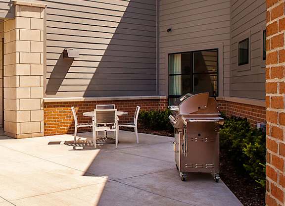 A patio with a table and chairs is outside a house.