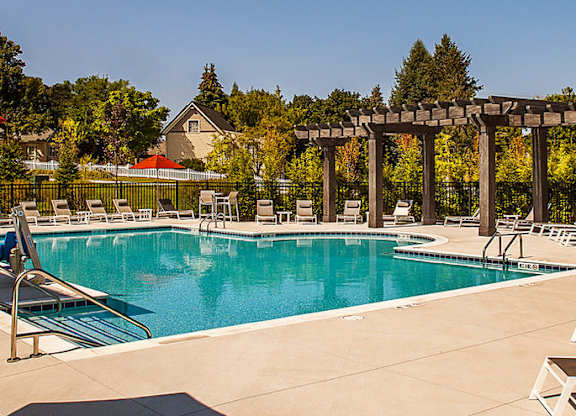 A large outdoor swimming pool surrounded by sun loungers and umbrellas.