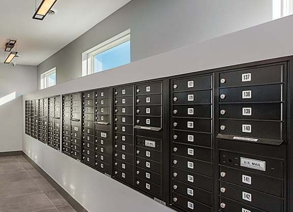 A long hallway with black mailboxes on the wall.