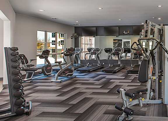 A gym with a variety of equipment including treadmills, weights, and exercise machines.