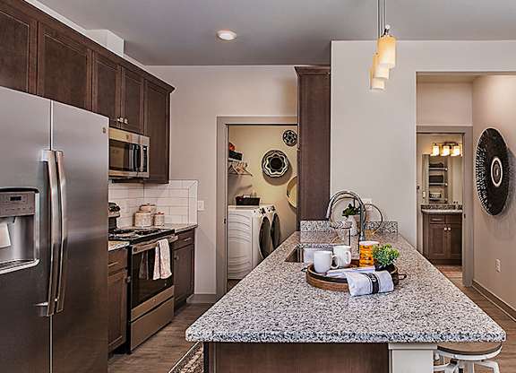 A kitchen with a granite counter top and stainless steel appliances.