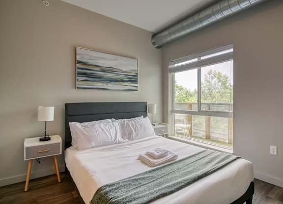 A bedroom with a large bed and a painting on the wall.
