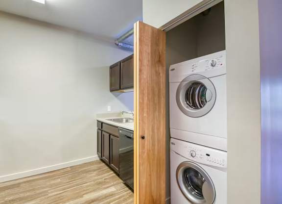 A white washer and dryer are stacked in a small laundry room.