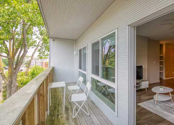 A balcony with a table and chairs overlooks a tree.