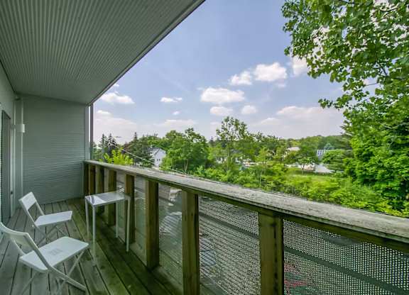 A balcony with a chair and a table overlooking a green landscape.