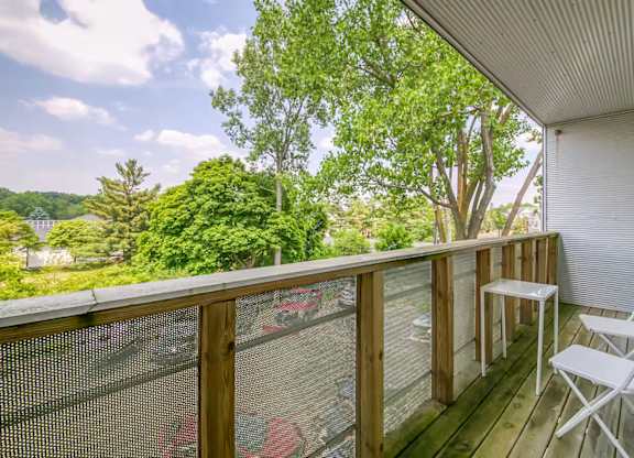 A white chair is on a wooden deck with a mesh screen door.