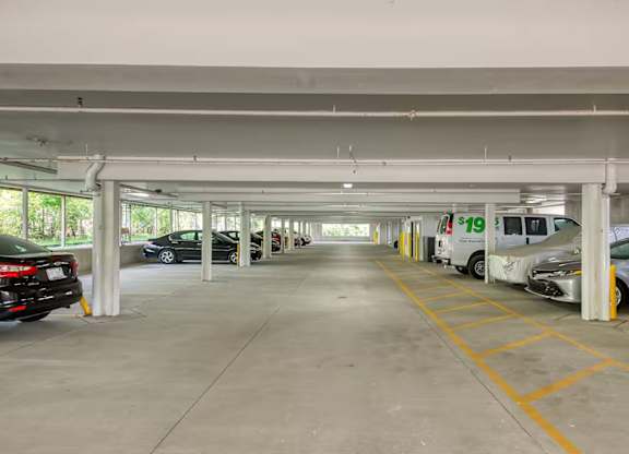 A parking garage with a white van and a black car.