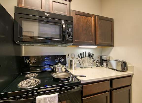 A black stove with a pot on it and a towel hanging on the oven handle.